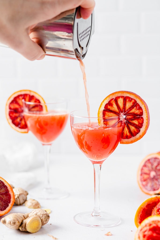 pouring blood orange cocktail into glass